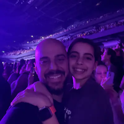 Mika and her dad at a concert, arms around each other, the arena lit violet behind them.